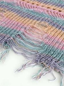 Détail d'un haut de plage au crochet à rayures avec maille ajourée et pompons à franges