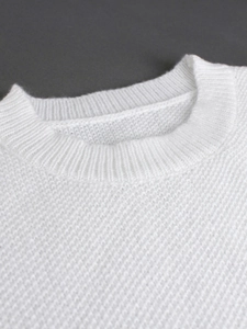 Close-up detail of white ribbed round neckline and textured knit fabric on sweater