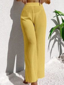 Detail of yellow knit wide leg beach pants featuring waffle texture and high waist