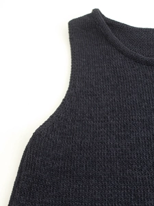 Close-up of black knit vest collar and shoulder showing fine ribbed texture detail