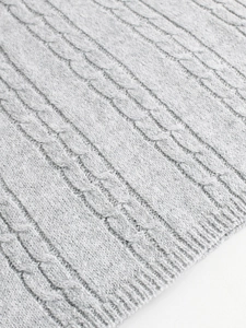 Detailed close-up of light grey cable knit fabric texture with soft vertical ribbing pattern