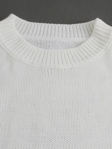 Close-up of white knit sweater showing ribbed crew neck collar and clean stitching