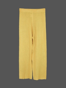 Close-up of yellow crochet knit beach trousers featuring intricate hollow out mesh texture