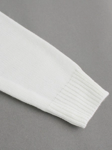 Close-up of white knit sweater cuff showing detailed ribbed texture and quality stitching