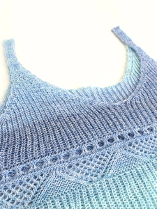Détail d'un débardeur en tricot dégradé bleu et blanc avec texture au crochet ajouré