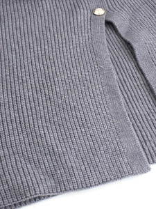 Detail of ribbed knit fabric texture with a golden embossed button on the side slit