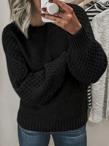 Detail shot of black crewneck knit sweater featuring a thick ribbed texture and cuffs