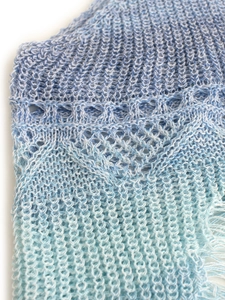 Détail du haut de plage en tricot dégradé bleu avec des finitions à franges délicates