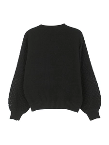 Detail view of black crewneck knit sweater featuring intricate hollow crochet lace sleeves