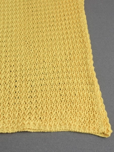 Macro shot of ginger yellow crochet knit fabric with hollow geometric patterns
