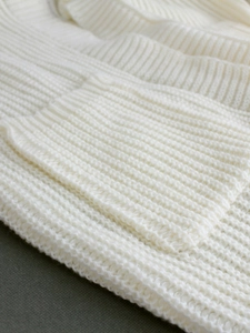 Detailed macro view of white vertical ribbed knit fabric texture and pocket stitching