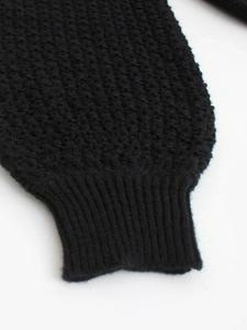 Detailed close-up of black waffle knit texture and ribbed cuff on long sleeve sweater