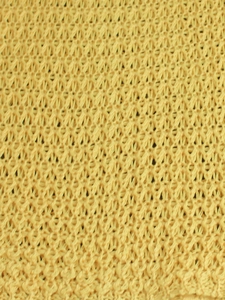Detailed macro view of yellow crochet knit fabric with hollow diamond mesh pattern