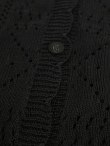 Detailed macro view of black knit cardigan featuring hollow-out patterns and button