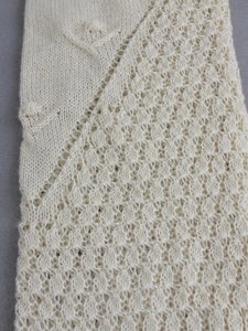 Detailed close-up of beige knitted fabric featuring hollow lace and geometric patterns