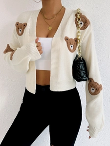 Close-up of beige knit cardigan with brown plush bear patches and ribbed cuffs