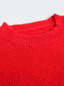 Close-up of red crew neck knitted sweater featuring thick textured pineapple stitch pattern