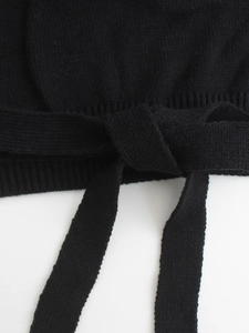 Detail of black knitted fabric texture with a tied bow ribbon on plain background