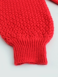 Macro shot of honeycomb textured red knit sleeve with elastic ribbed cuffs for women