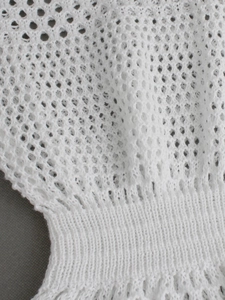 Detail of white crochet knit sleeveless dress showing hollow mesh pattern and ribbed hem
