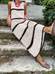 Detail of crochet knit maxi dress with black stripes and hollow out texture on beige fabric