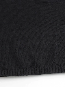 Detailed close-up of black knit sweater vest showing texture and ribbed hem edge