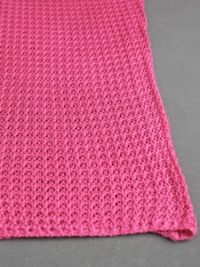 Close-up of rose red knitted mesh fabric with intricate hollow-out floral crochet patterns