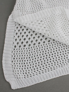 Close-up of white hollow knit fabric showing detailed crochet texture and ribbed edge