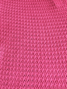 Macro shot of hot pink hollow crochet knit fabric with honeycomb texture for beach pants