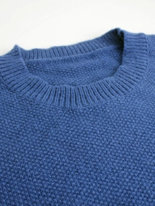 Detailed close-up of the royal blue ribbed crew neck and soft knit texture of the sweater