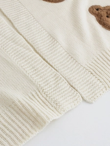 Detailed close-up of knitted fabric with a cute teddy bear embroidery and ribbed texture