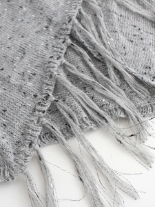 Maglione in maglia grigio chiaro con trama tweed e lunghe frange su sfondo bianco