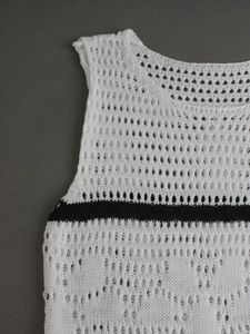Close-up of white knit hollow-out vest with black stripe and large mesh texture