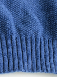 Macro view of blue knit sweater ribbed cuff and detailed thick woven fabric texture