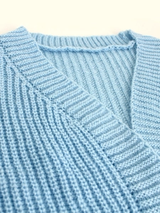 Detail of light blue chunky knit cardigan showing V-neckline and ribbed texture