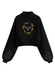Détail de broderie fleurs et abeilles sur pull à col roulé en maille côtelée noire