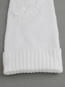 Détail de jambière en tricot blanc avec applique délicate de fleur en dentelle 3D
