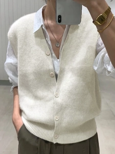 Detail view of off-white V-neck knitted vest with buttons layered over a white shirt