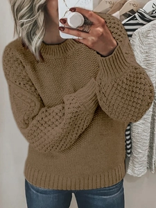 Close-up of brown chunky knit sweater with puff sleeves and crew neck design