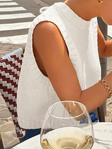 Detail of white knit sleeveless top featuring classic round neck and ribbed edge texture