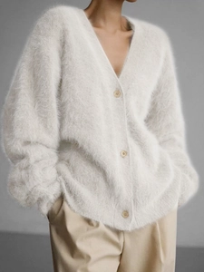 Detail of soft cream knitted V-neck cardigan featuring plush texture and elegant buttons