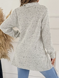 Dettaglio di un maglione grigio chiaro a maglia con texture a coste e frange sul retro