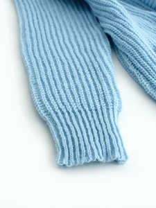 Detail view of light blue ribbed knit sleeves and thick woven texture on the cardigan