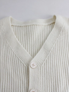 Detail of V-neckline and cream rib-knit texture with matching buttons on a sleeveless vest