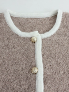 Women's knit cardigan neck detail featuring light camel bouclé fabric and gold buttons