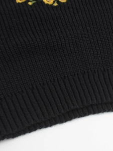 Détail de poignets en maille côtelée avec broderie florale sur un pull à col roulé