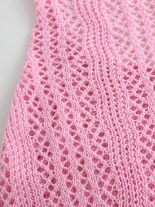 Detailed close-up of pink hollow-out knitted fabric with elegant diamond pattern