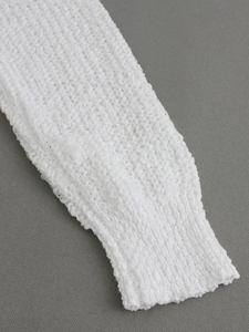 Primer plano detallado de la suave textura de punto blanco y el puño del jersey con cuello en V