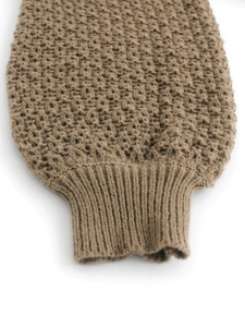 Close-up of brown chunky knit sweater showing rib-knit cuffs and detailed texture