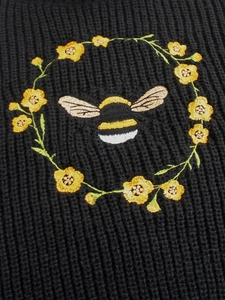 Vue détaillée de la broderie d'abeille et de fleurs sur le tissu en maille côtelée